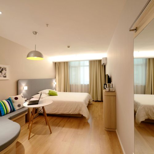 Spacious modern hotel room featuring cozy decor and neutral tones with natural light.