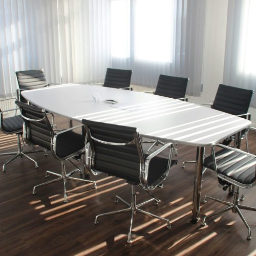 Modern office meeting room with designer chairs, table, and large windows.