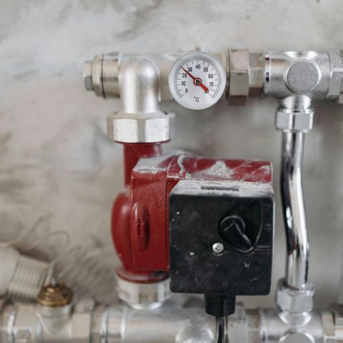 Close-up view of an industrial plumbing system featuring a pressure gauge and steel pipes.